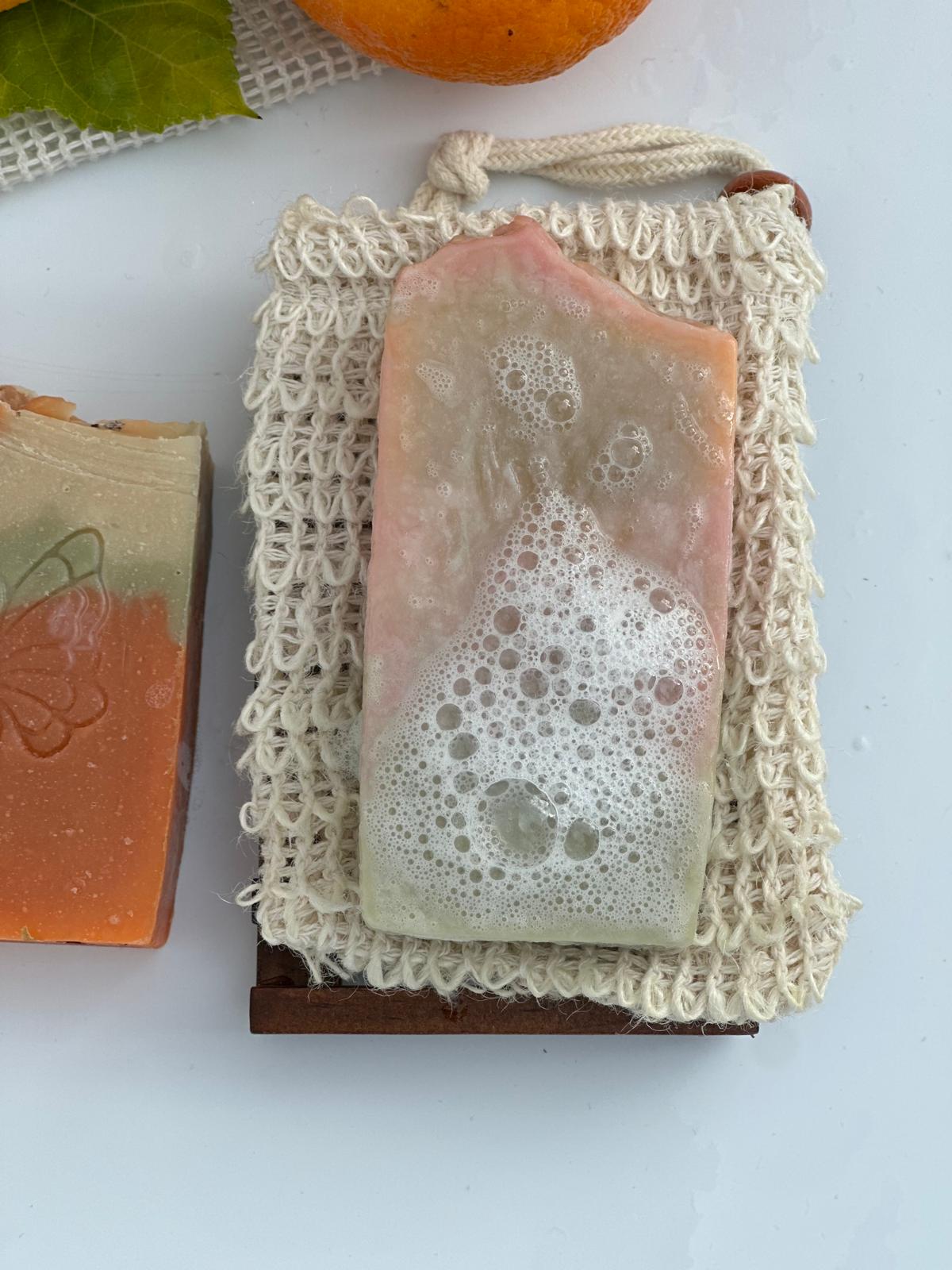 Handgemachte Orangenblütenseife mit feinem Schaum auf einem natürlichen Seifensäckchen.