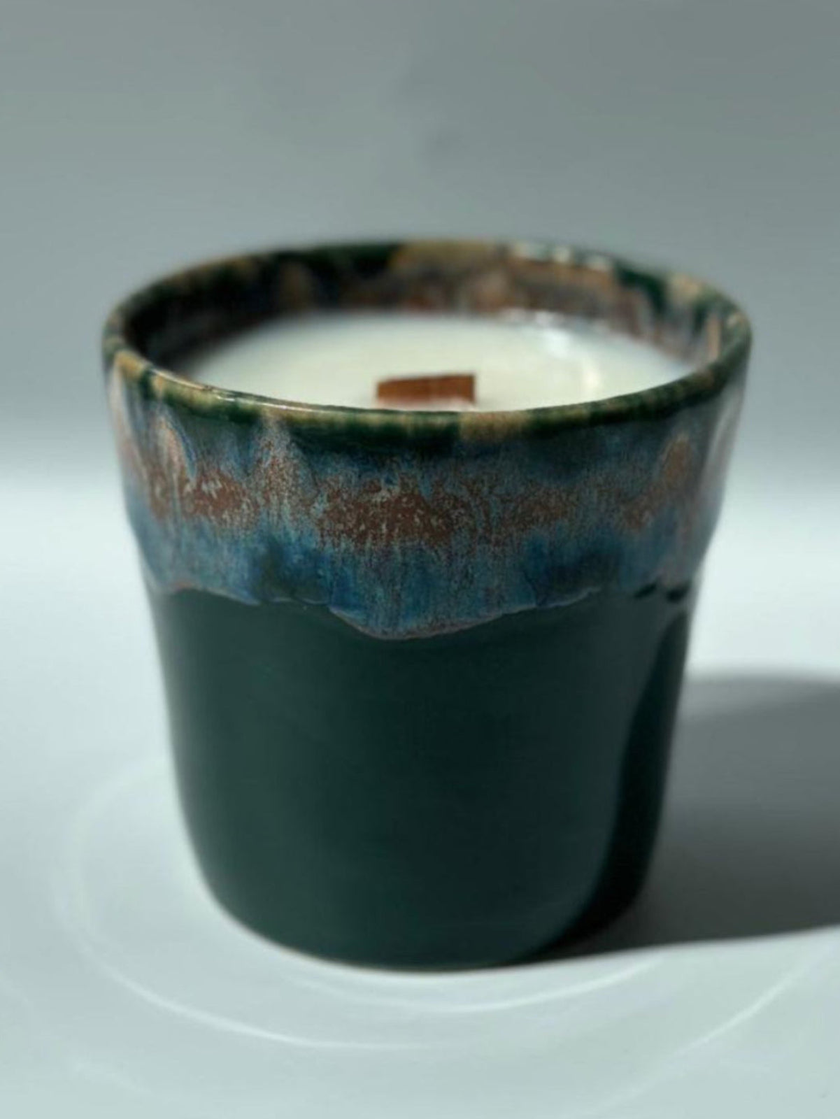 Dark ceramic cup with a candle inside on a white background